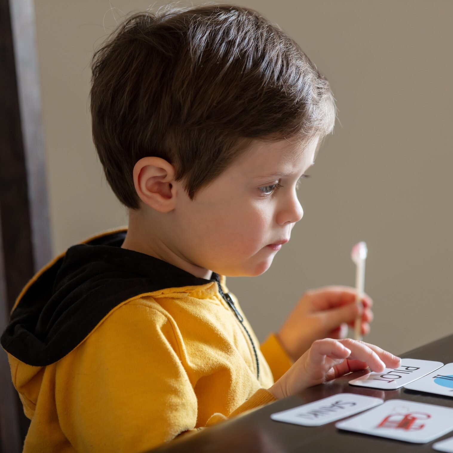 little boy learns words from cards under the ABA therapy program at home at the table